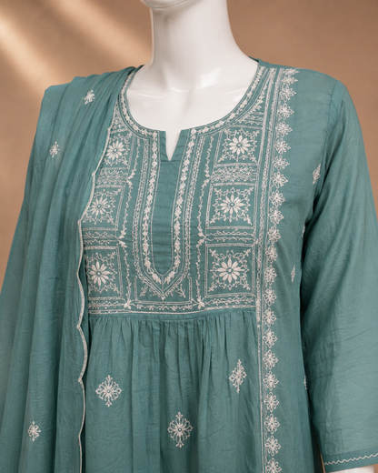 A teal green embroidered kurta set with a matching dupatta displayed on a white mannequin. The kurta features intricate white embroidery around the neckline, along the front panel, and scattered motifs on the lower portion.