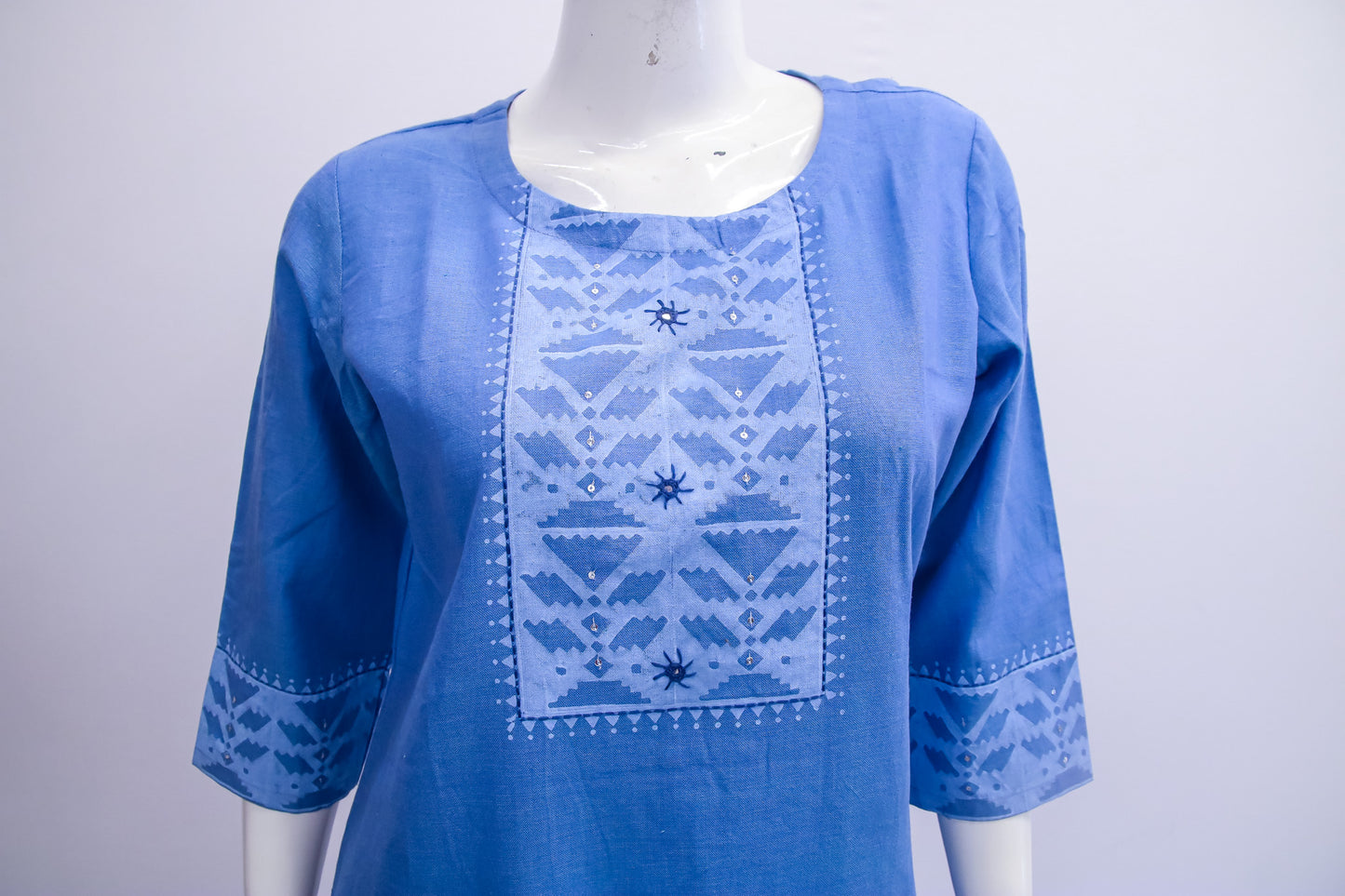Blue embroidered blouse on a mannequin against a white background