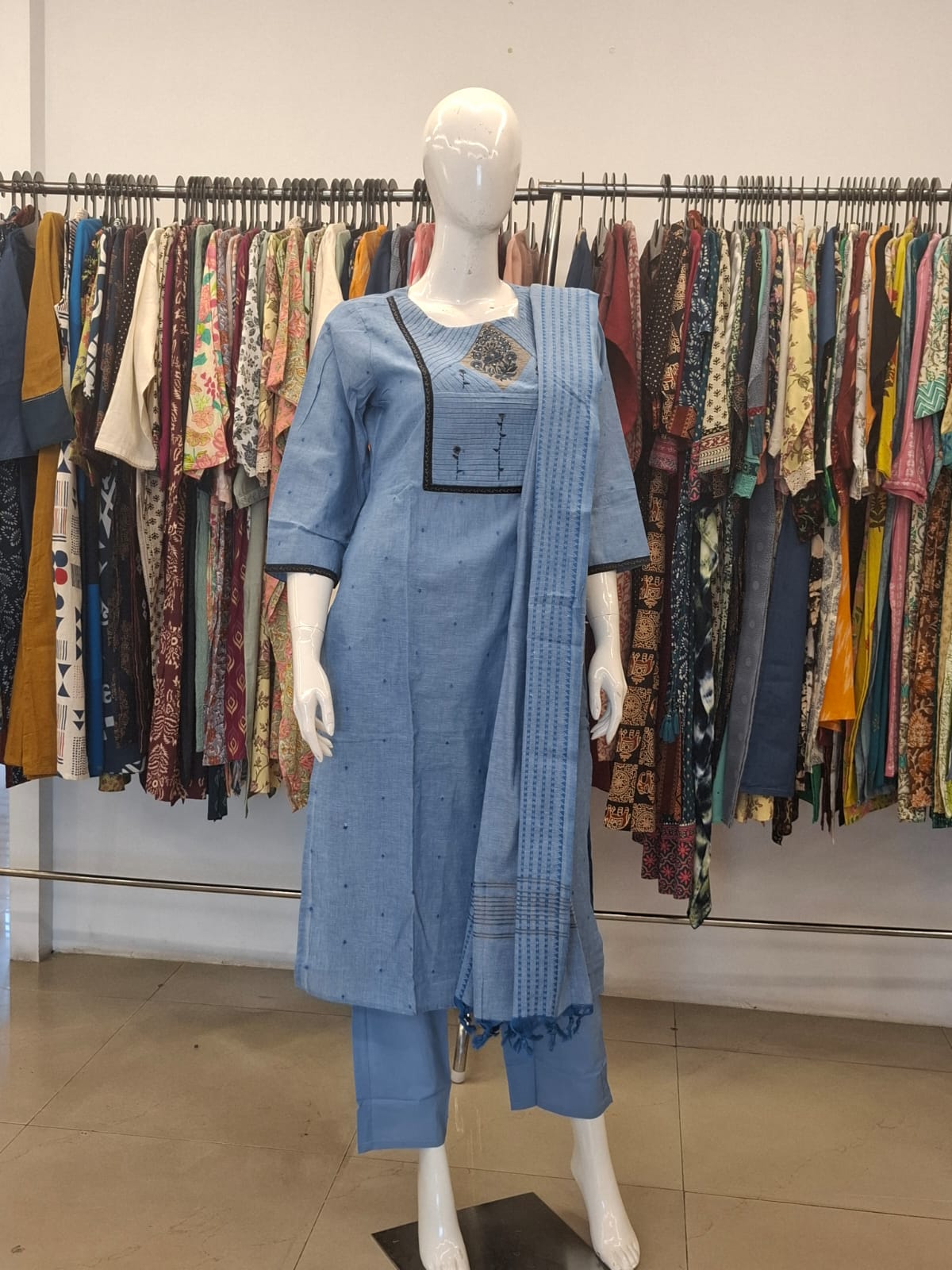 Mannequin wearing a blue outfit with a matching dupatta in a clothing store setting.