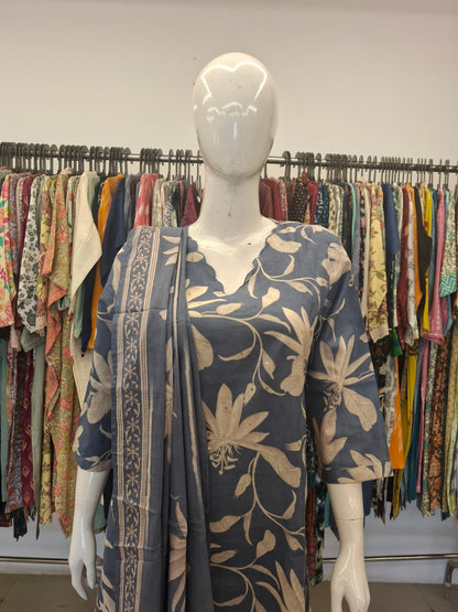 Mannequin wearing a floral dress with a colorful background of hanging clothes