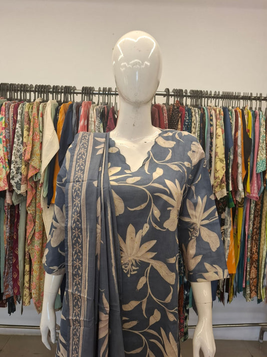 Mannequin wearing a floral dress with a colorful background of hanging clothes