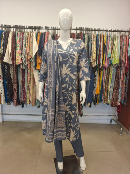 Mannequin wearing a floral dress with a rack of clothes in the background