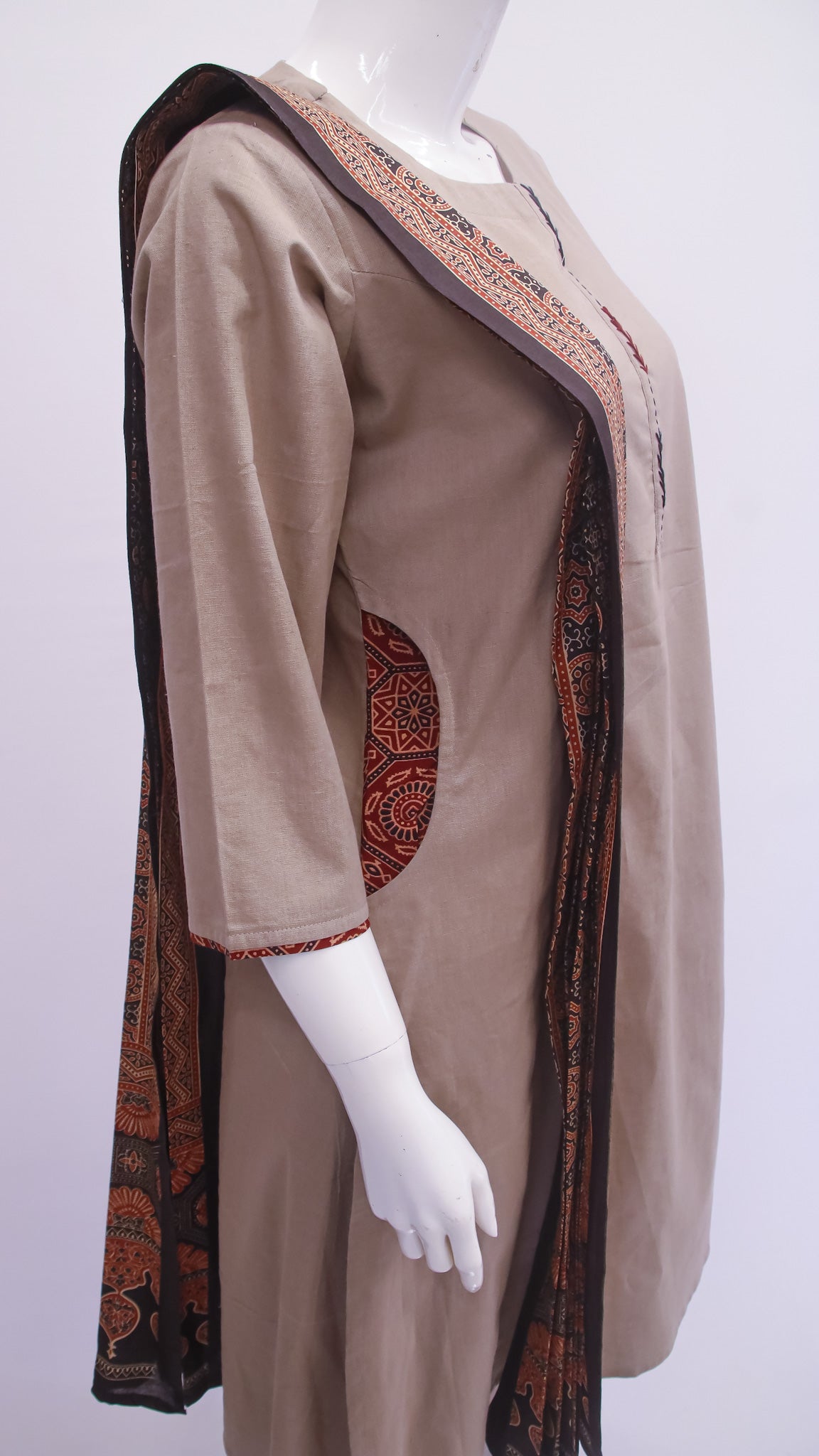 Mannequin wearing a beige dress with a patterned trim on a white background