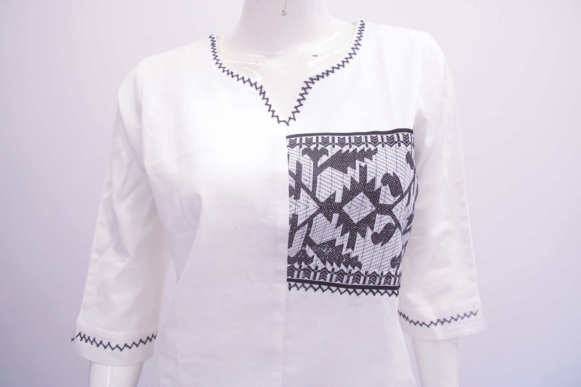 White sweater with black geometric pattern on a mannequin against a white background