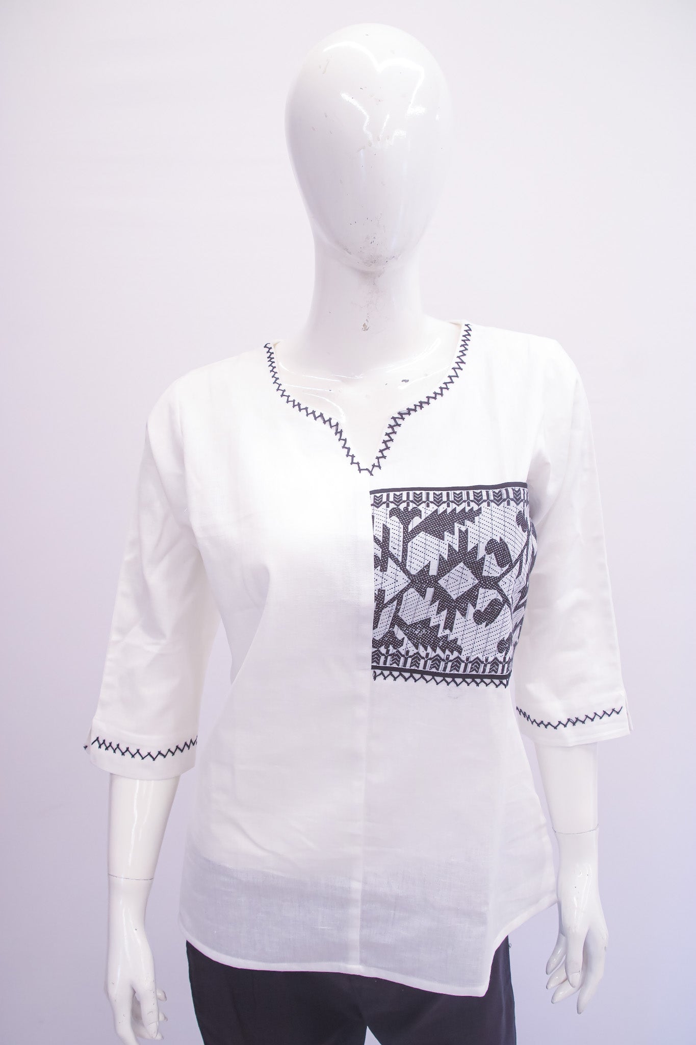 White blouse with black pattern on a mannequin against a white background