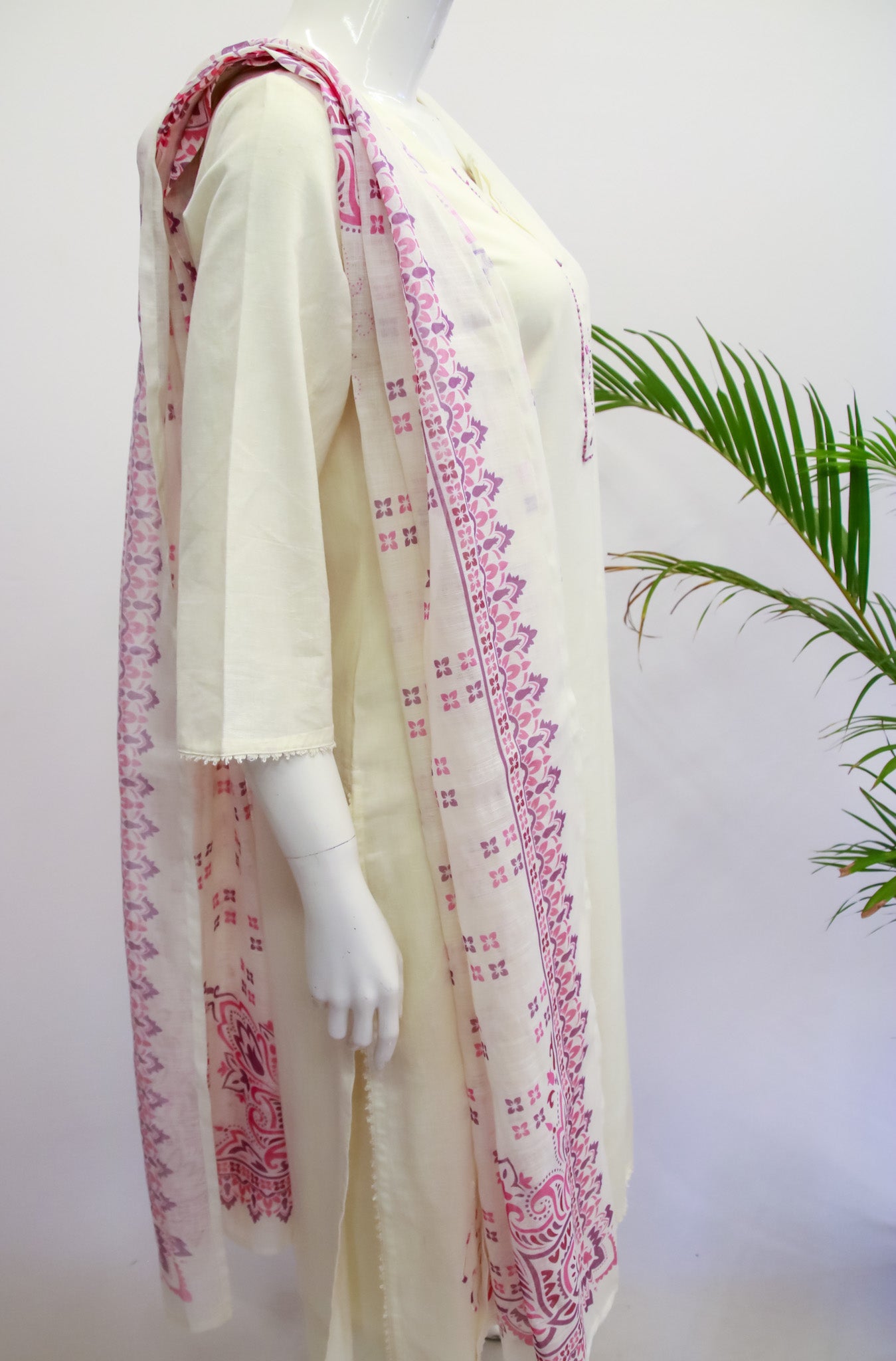 White saree with pink and red border on a mannequin against a white background