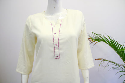 Light yellow kurta with red embroidery on a mannequin against a white background