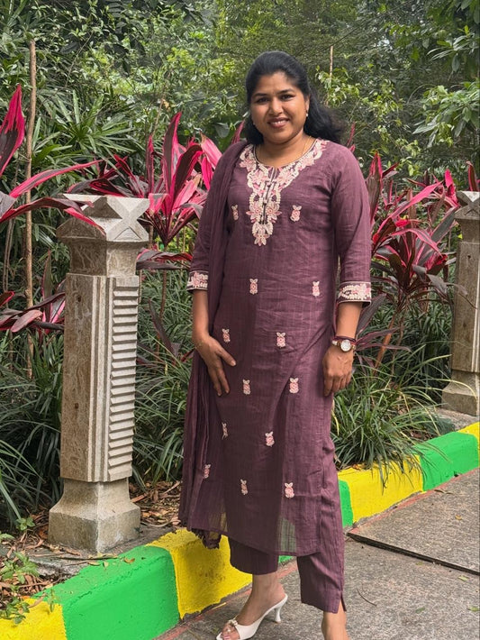 Woman in a purple dress standing in front of greenery