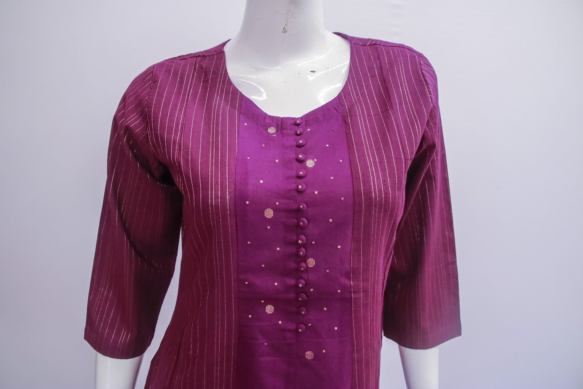 Purple blouse with button details on a mannequin against a white background